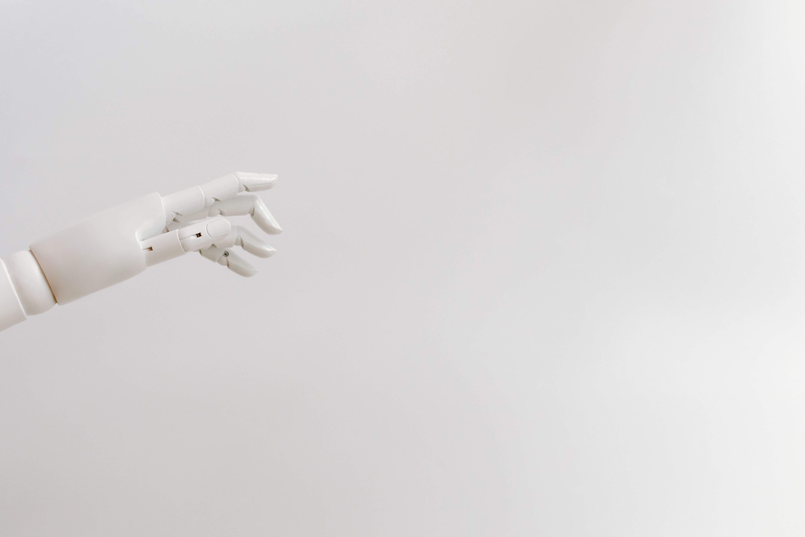 Minimalist image of a robotic hand reaching out on a white background.