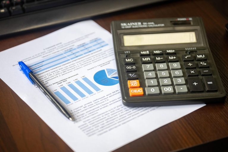 Calculator, pen and financial documents on an office desk
