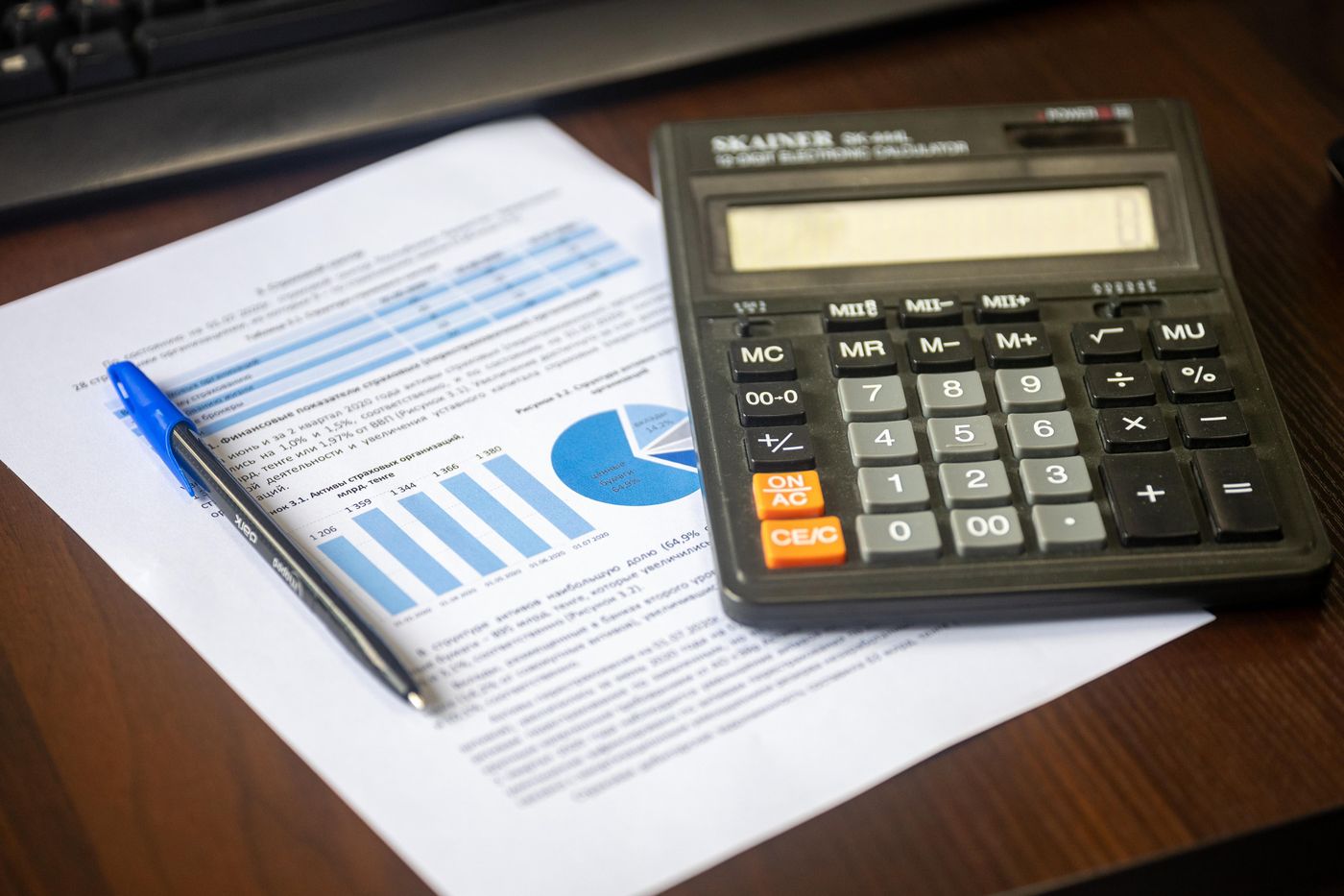 Calculator, pen and financial documents on an office desk