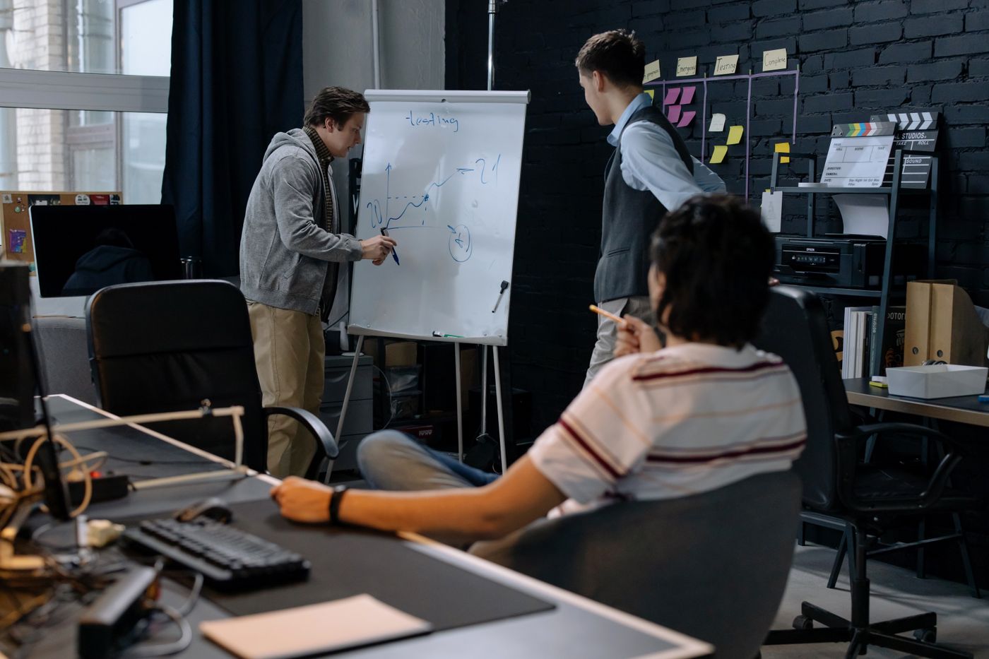 Colleagues discussing a plan at a whiteboard in an office