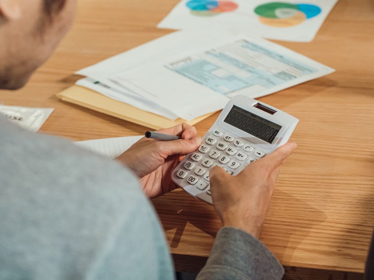 Person reviewing financial documents with a calculator at a desk